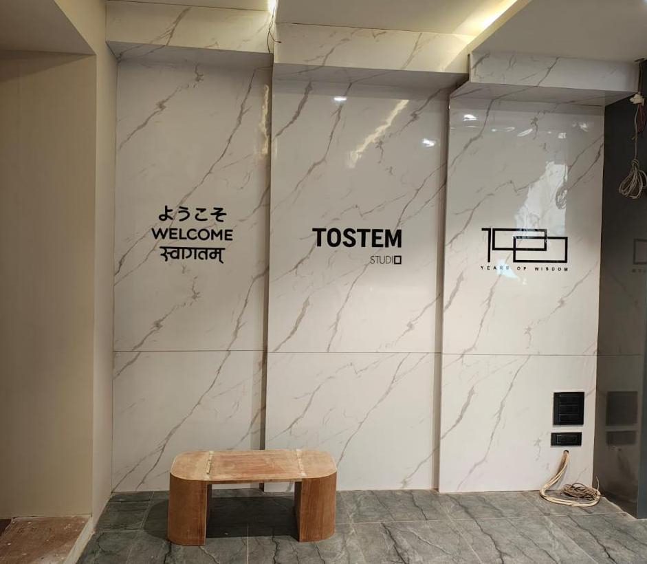 TOSTEM Studio logo and multilingual welcome lettering mounted on a marble-finish wall